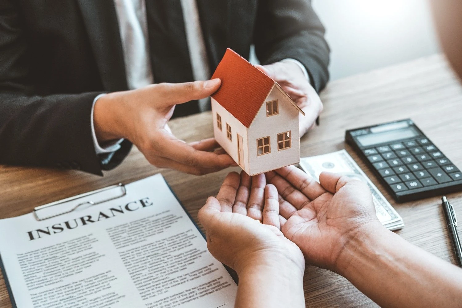 Model house handed over beside a home insurance document